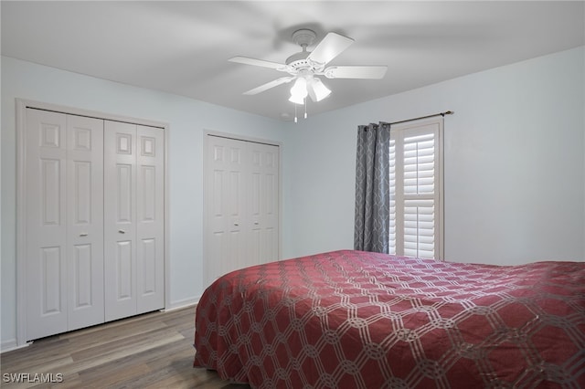 bedroom with ceiling fan, light wood-type flooring, and two closets