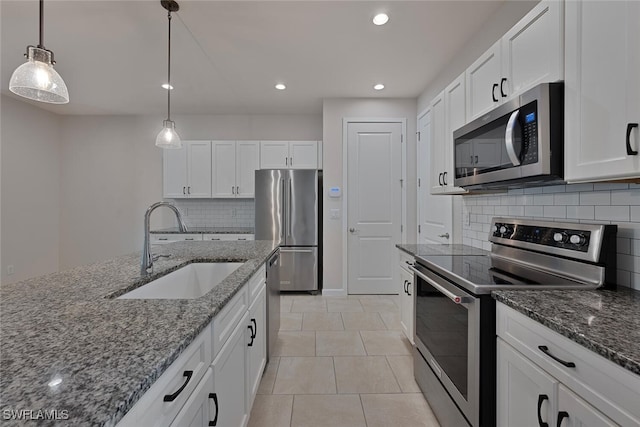 kitchen with appliances with stainless steel finishes, sink, pendant lighting, white cabinets, and dark stone countertops