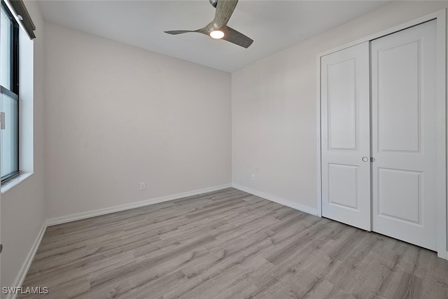 unfurnished bedroom with light hardwood / wood-style flooring, multiple windows, and a closet