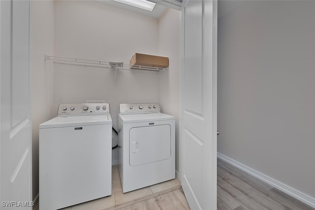 clothes washing area with separate washer and dryer and light wood-type flooring