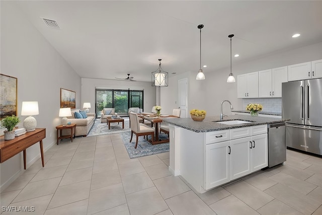 kitchen featuring an island with sink, dark stone countertops, sink, white cabinets, and appliances with stainless steel finishes