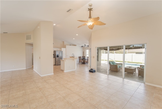 unfurnished living room with ceiling fan, high vaulted ceiling, and light tile patterned floors