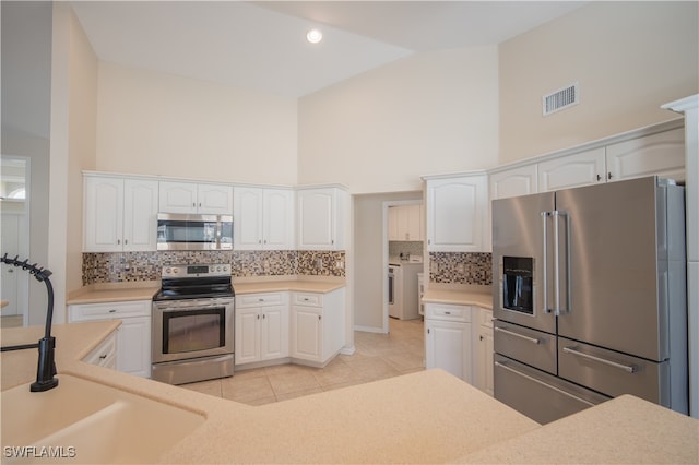 kitchen with white cabinets, stainless steel appliances, high vaulted ceiling, and sink