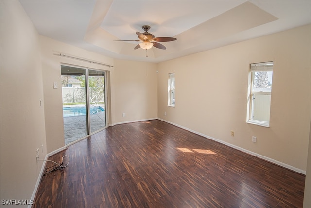 empty room with ceiling fan, plenty of natural light, and dark hardwood / wood-style flooring