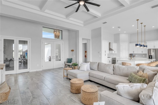 living room with a towering ceiling, french doors, ceiling fan, coffered ceiling, and beamed ceiling