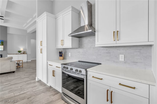 kitchen featuring backsplash, wall chimney range hood, stainless steel electric range, and white cabinets