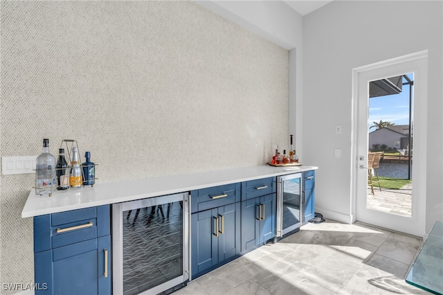 bar featuring blue cabinets and beverage cooler