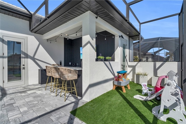 view of patio with ceiling fan, exterior bar, and a lanai