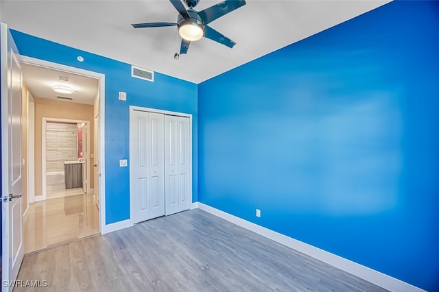 unfurnished bedroom with hardwood / wood-style floors, white refrigerator, a closet, and ceiling fan