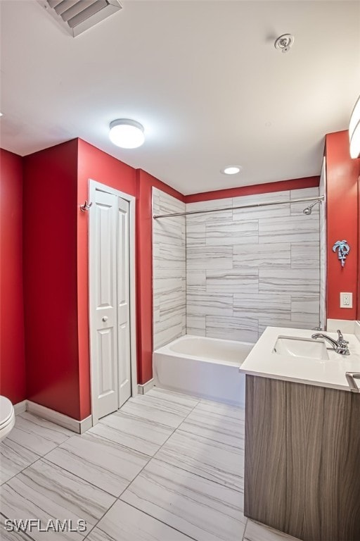 full bathroom featuring vanity, tiled shower / bath combo, and toilet