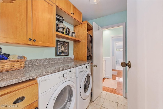 washroom featuring light tile patterned floors, washer and clothes dryer, and cabinets