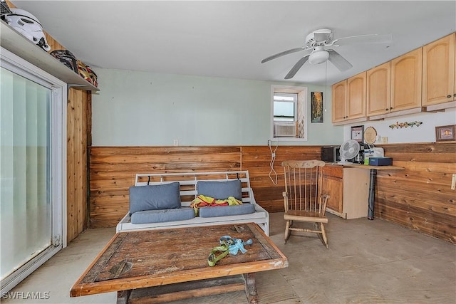 kitchen with ceiling fan, cooling unit, light brown cabinetry, and wood walls