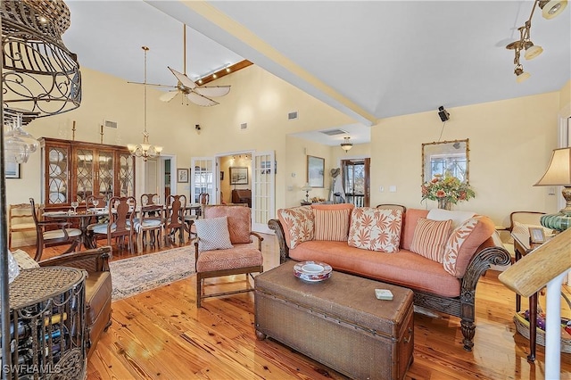 living room with ceiling fan with notable chandelier and hardwood / wood-style floors