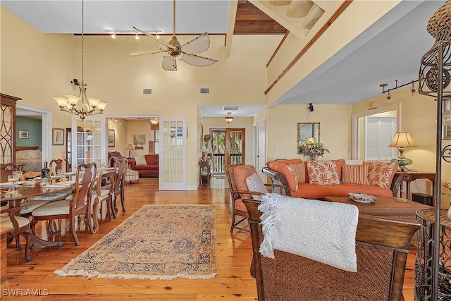 living room with ceiling fan with notable chandelier, light hardwood / wood-style floors, and french doors