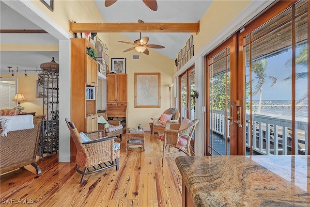 interior space featuring a water view, ceiling fan, lofted ceiling with beams, and light wood-type flooring