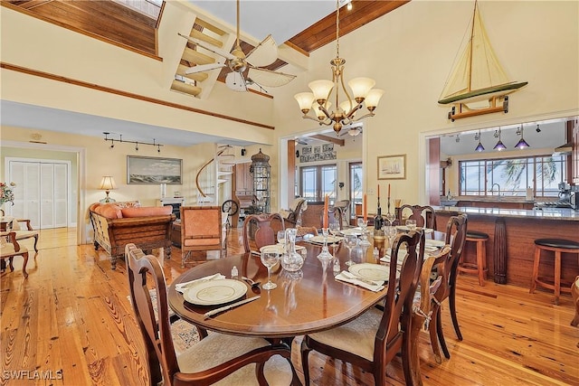 dining room with a towering ceiling, a wealth of natural light, and light hardwood / wood-style floors