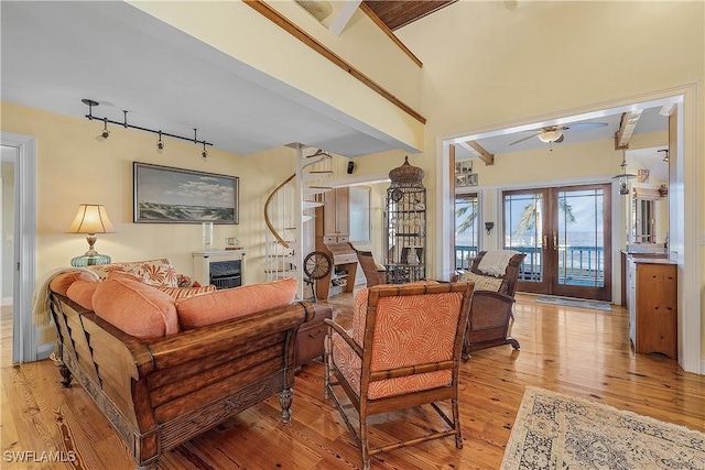 living room with french doors, ceiling fan, rail lighting, and light wood-type flooring