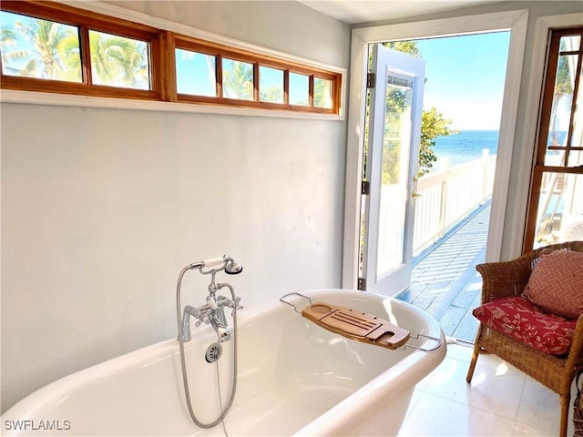 bathroom featuring a bathtub, tile patterned floors, and a water view