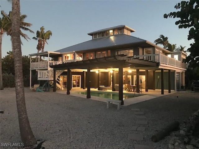 back house at dusk featuring a pool side deck, a patio area, and a pergola