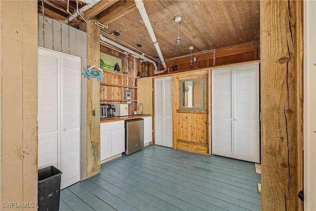 kitchen with dishwasher, hardwood / wood-style floors, white cabinets, and wood walls