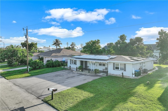 ranch-style house featuring solar panels and a front lawn