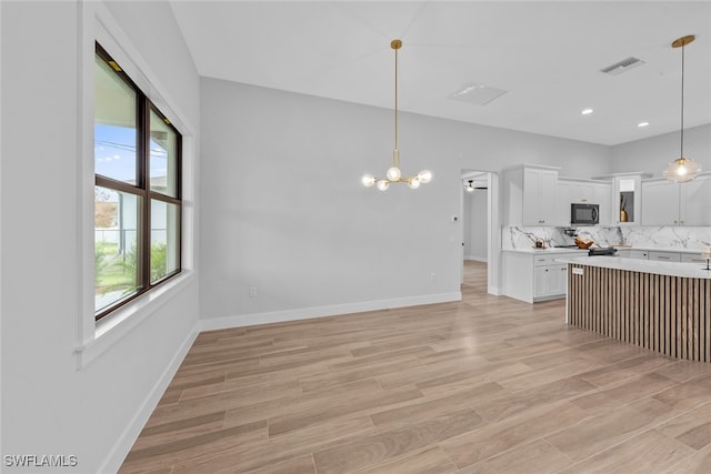 kitchen with white cabinetry, decorative backsplash, light wood-type flooring, and hanging light fixtures