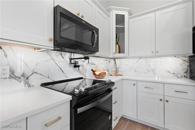 kitchen featuring black appliances, light stone countertops, light wood-type flooring, white cabinets, and tasteful backsplash