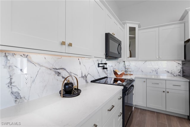 kitchen with black appliances, white cabinetry, dark wood-type flooring, and backsplash