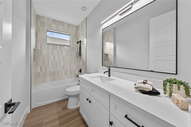 full bathroom featuring toilet, hardwood / wood-style floors, tiled shower / bath combo, and vanity