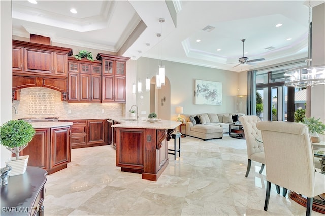 kitchen featuring ceiling fan with notable chandelier, pendant lighting, sink, kitchen peninsula, and a tray ceiling