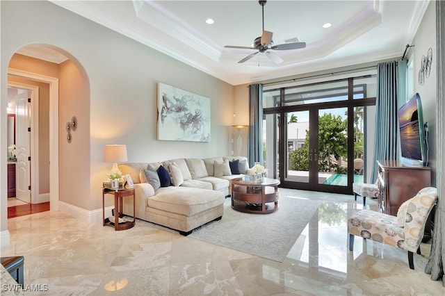 living room with ceiling fan, ornamental molding, french doors, and a tray ceiling