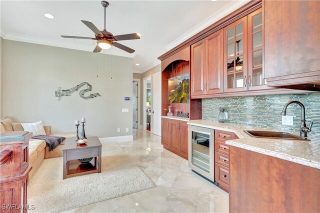 kitchen with backsplash, beverage cooler, light stone countertops, ornamental molding, and sink