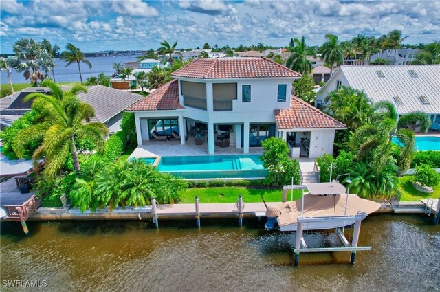 rear view of house with a water view, a balcony, and a patio