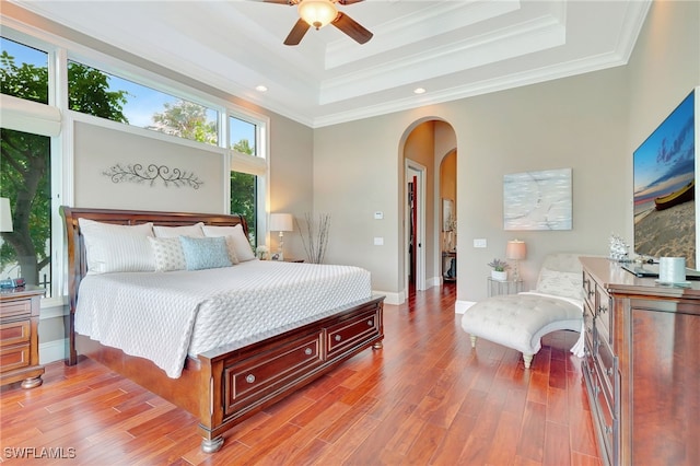 bedroom featuring ceiling fan, light hardwood / wood-style flooring, crown molding, and a raised ceiling