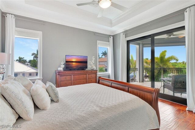 bedroom with hardwood / wood-style floors, ceiling fan, a raised ceiling, access to outside, and ornamental molding