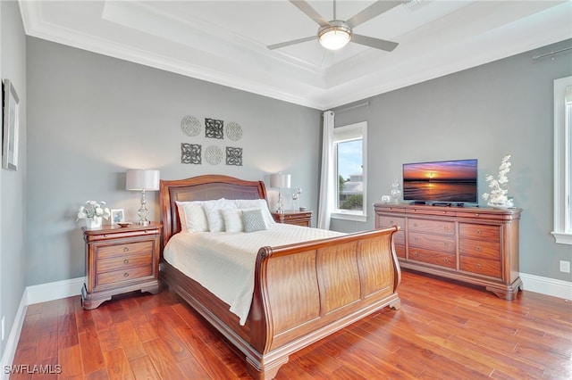 bedroom with ceiling fan, ornamental molding, hardwood / wood-style floors, and a tray ceiling