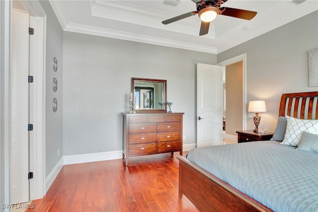 bedroom featuring hardwood / wood-style flooring, ceiling fan, ornamental molding, and a raised ceiling