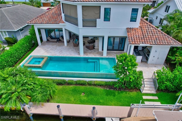 rear view of house with a swimming pool with hot tub and a patio