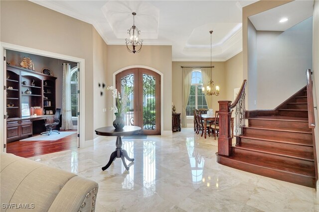 foyer with a notable chandelier, ornamental molding, and french doors