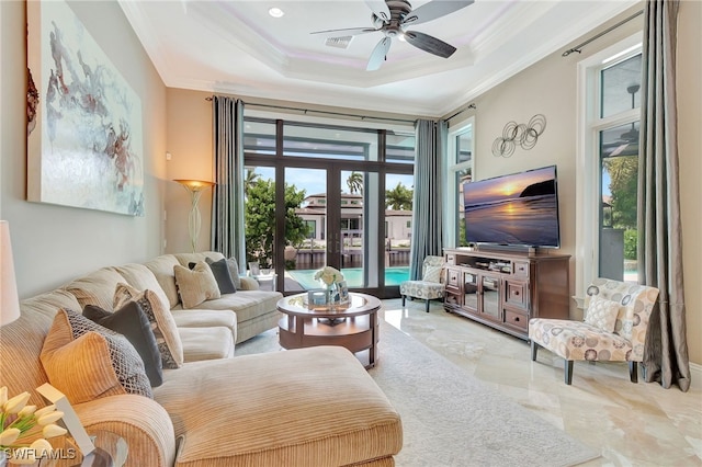 living room with ceiling fan, a tray ceiling, crown molding, and french doors