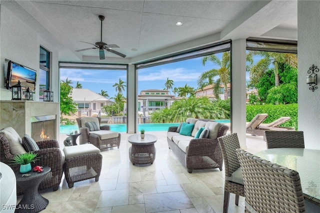 sunroom with ceiling fan and an outdoor fireplace