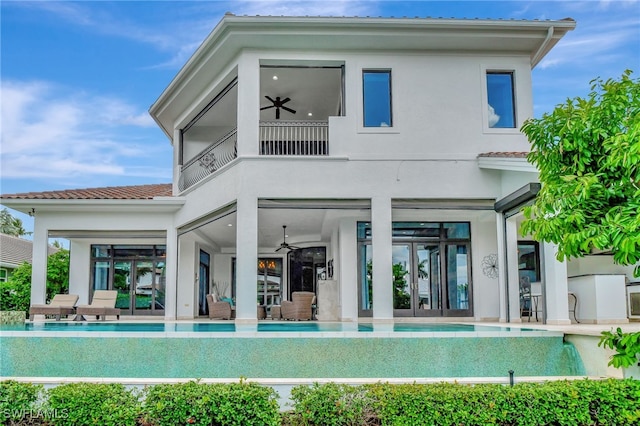 rear view of property with ceiling fan, french doors, and a balcony