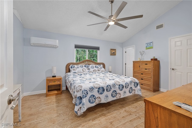 bedroom with lofted ceiling, an AC wall unit, a textured ceiling, light hardwood / wood-style floors, and ceiling fan