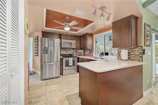 kitchen featuring sink, stainless steel appliances, decorative backsplash, and a tray ceiling