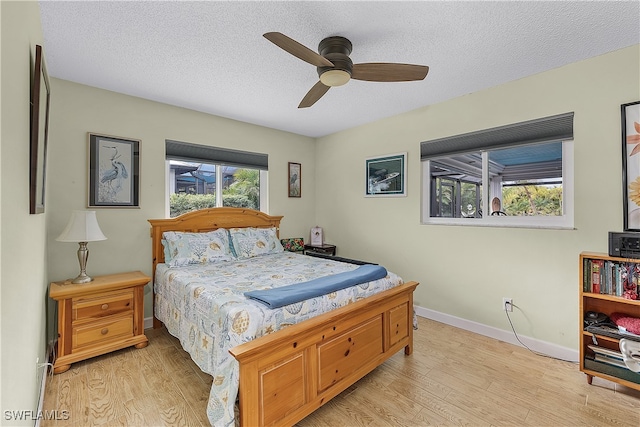 bedroom featuring a textured ceiling, light wood-type flooring, and ceiling fan