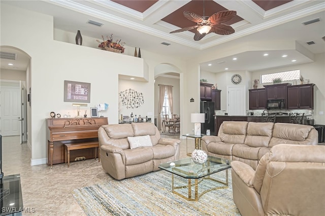 living room featuring beamed ceiling, coffered ceiling, crown molding, and ceiling fan