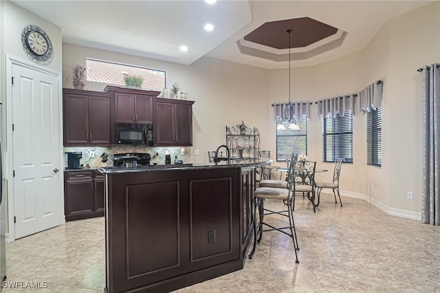 kitchen featuring hanging light fixtures, black appliances, a center island with sink, and plenty of natural light