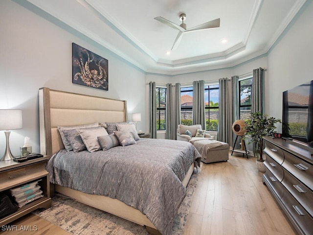 bedroom featuring light hardwood / wood-style floors, crown molding, a tray ceiling, and ceiling fan