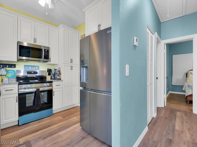 kitchen with light hardwood / wood-style flooring, appliances with stainless steel finishes, light stone counters, and white cabinets