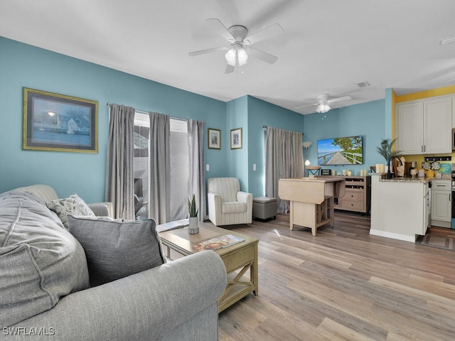 living room featuring ceiling fan, sink, and light hardwood / wood-style flooring